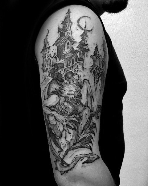 Black and grey upper arm tattoo featuring a menacing gargoyle perched in front of a gothic castle with towering spires and a crescent moon.