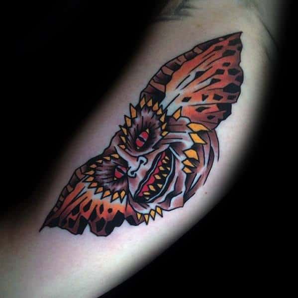 Bold Gremlin tattoo with sharp teeth, fiery orange tones, and striking patterns, creating a fierce and dynamic look.
