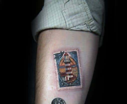 Realistic tattoo of a vintage postage stamp with intricate details on the arm.