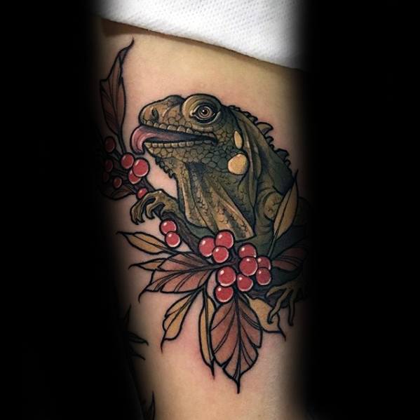 Traditional-style iguana tattoo with bold outlines, perched among red berries and leaves, tongue playfully sticking out