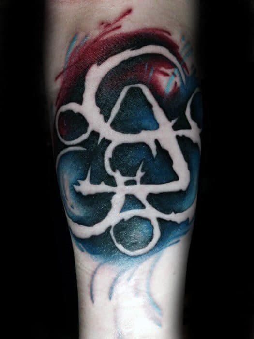 Vibrant Keywork tattoo with negative space design, surrounded by deep blue and red watercolor-style shading for a dramatic Coheed and Cambria look.