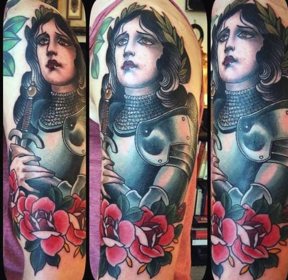Colorful Joan of Arc tattoo in neo-traditional style, featuring her in armor with a sword, roses, and laurel crown.