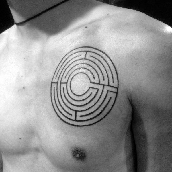 Minimalist circular labyrinth tattoo on a man's chest, featuring clean black lines forming a maze pattern with an open center design.