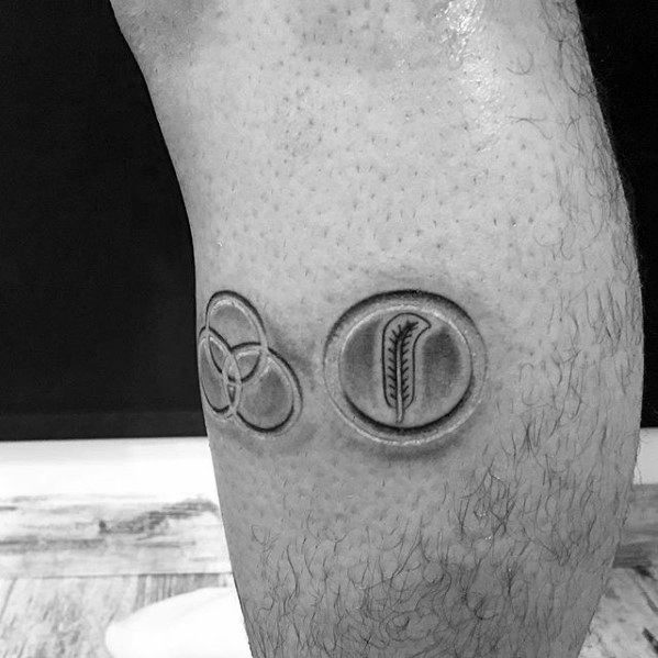 Calf tattoo of two Led Zeppelin symbols—Borromean rings and feather in a circle—done in a 3D embossed style with subtle shading.