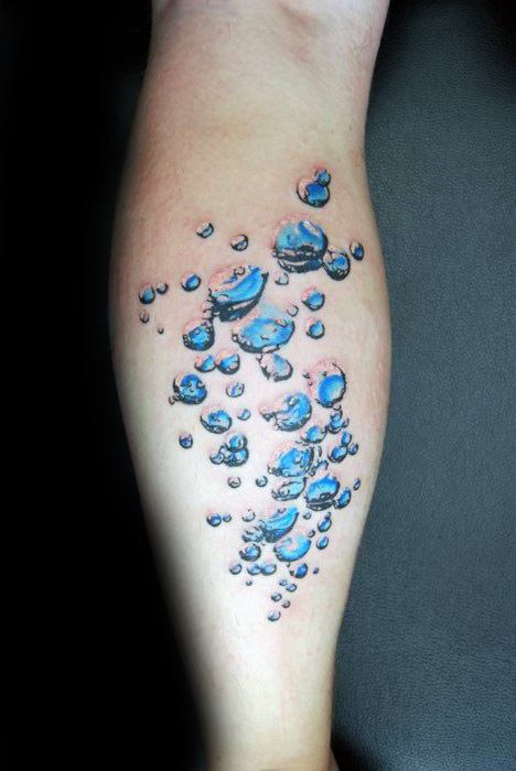 Tattoo of water droplets in various sizes, arranged in a flowing pattern, with detailed shading and reflections to create a realistic, three-dimensional effect.