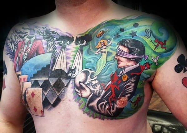 Colorful chest tattoo of a blindfolded magician, playing cards, cats, and surreal mystical elements