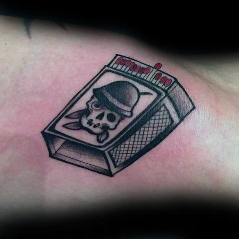 Traditional-style matchbox tattoo featuring a skull with a helmet on the cover, symbolizing danger, rebellion, or living on the edge.