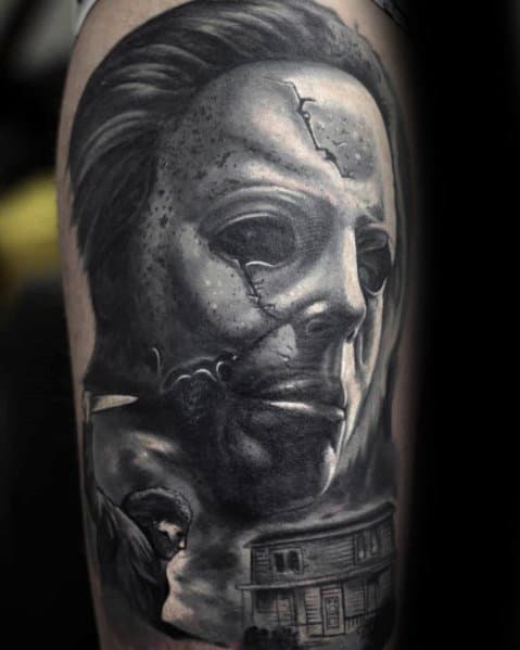 Highly detailed black and gray Michael Myers tattoo, featuring his cracked mask, knife, and the eerie house from the Halloween series.