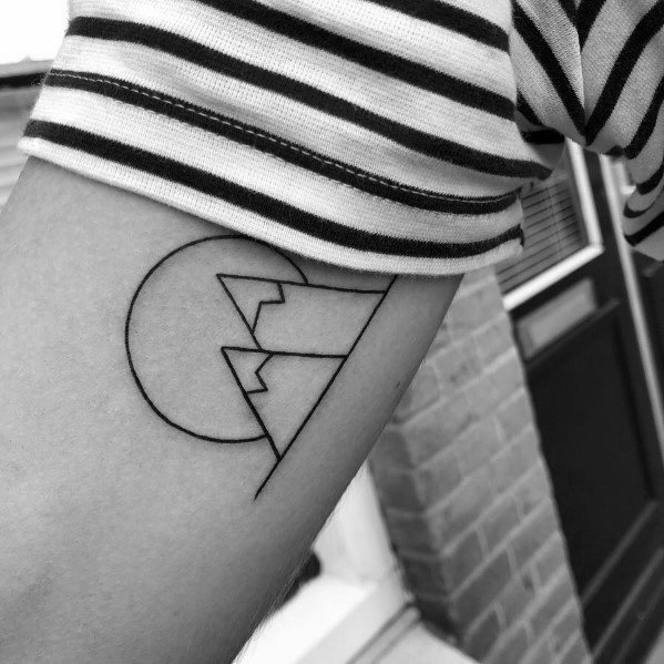 Minimalist mountain tattoo on the arm, featuring geometric peaks inside a half-circle, creating a clean and modern landscape design.