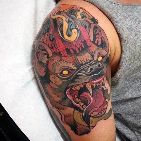 Neo-traditional tattoo of a snarling bat with fiery red crown, sharp fangs, and glowing yellow eyes on the upper arm.