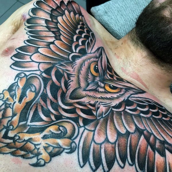 Neo-traditional owl chest tattoo with outstretched wings, sharp talons, and bold shading, creating a fierce and dynamic design.