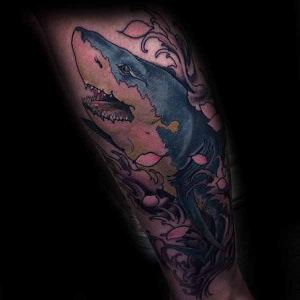 Neo-traditional shark tattoo with pink and blue hues, surrounded by swirling floral and wave elements on a dark background.