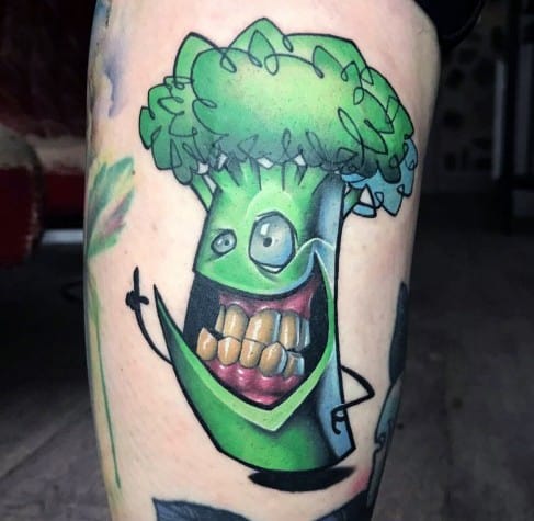 Cartoon-style broccoli tattoo with exaggerated features, a mischievous grin, and vibrant colors for a bold and playful design.