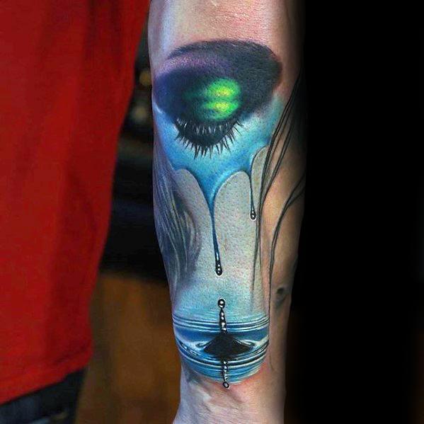 Surreal eye tattoo with green iris melting into blue drips, forming water drops and ripples at the bottom.