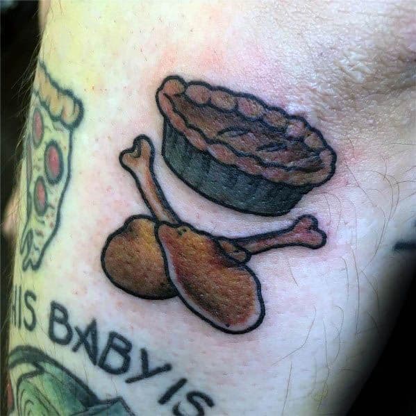 Chicken and pie tattoo featuring a classic pie and two drumsticks, combining comfort food elements in a bold, nostalgic design