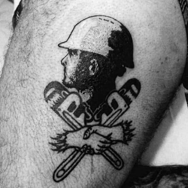 Black and grey tattoo of a construction worker's profile above two crossed pipe wrenches and a firm handshake.