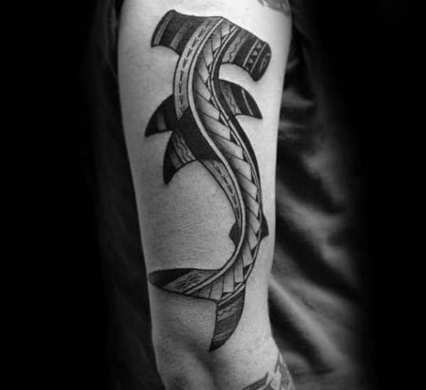 Polynesian hammerhead shark tattoo on upper arm with bold tribal detailing symbolizing protection, power, and determination.
