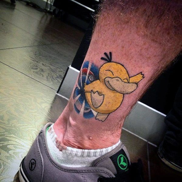 Playful Psyduck tattoo with a winking expression and raised arm, set against a Poké Ball background on a man's lower leg.