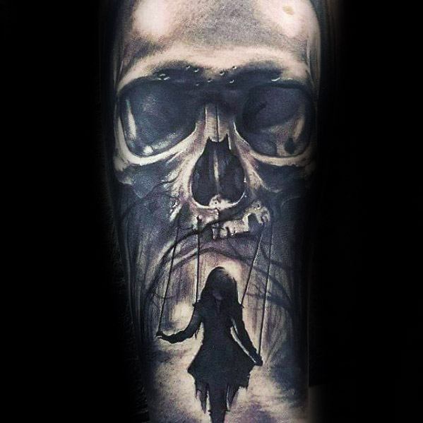 Dark puppet tattoo showing a skull controlling a silhouetted girl with strings, symbolizing death’s grip or unseen control.