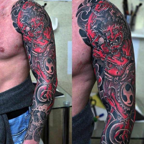 Intense Raijin full sleeve tattoo in red and black, featuring fierce expression, swirling patterns, and traditional Japanese motifs.