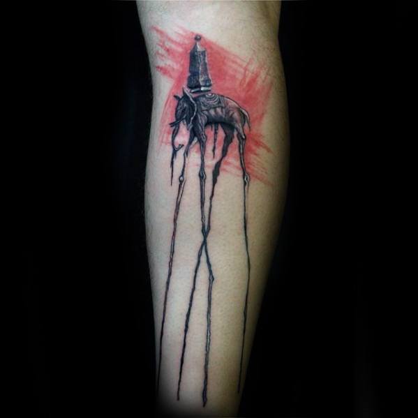 Black and grey Salvador Dali-style elephant tattoo with elongated legs and an obelisk, set against a red brushstroke background.