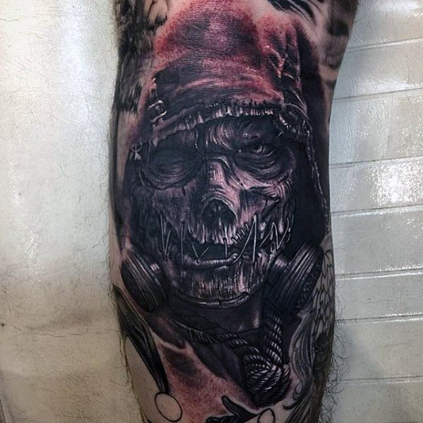 Terrifying scarecrow tattoo with stitched mouth, hollow eyes, hood, gas mask, and dark shading with subtle red highlights.