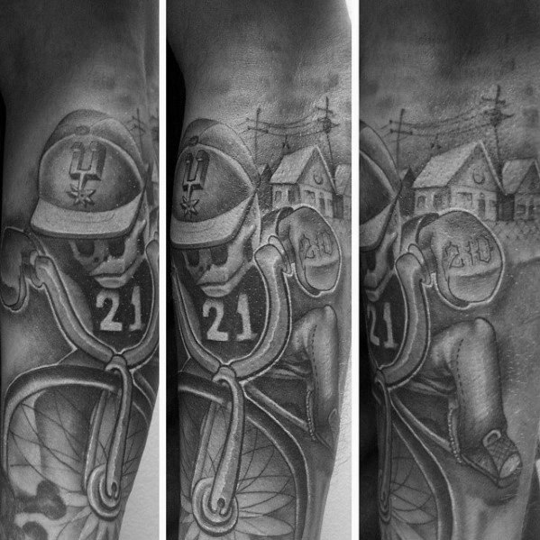 Black and grey tattoo of a skeleton football player wearing a Spurs helmet and jersey number 21, with a suburban neighborhood in the background.