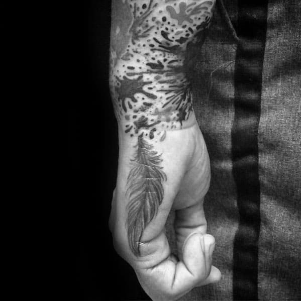 Close-up of a forearm tattoo depicting a feather and splash-like design in black ink