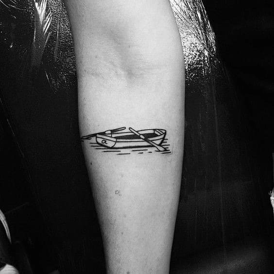 Alt text: Simple black ink tattoo of a canoe floating on water with two paddles, emphasizing minimalistic design and clean lines.