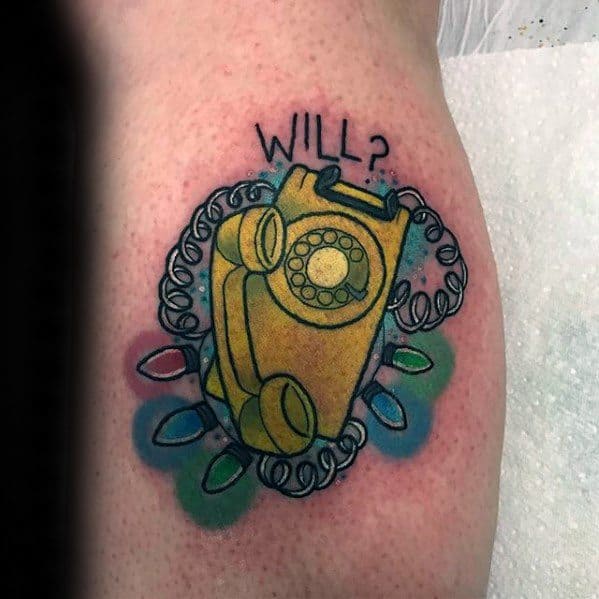 Tattoo of a yellow rotary phone with Christmas lights and the word “Will?” above, referencing Stranger Things' iconic scene.
