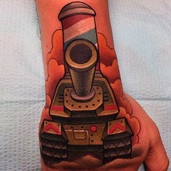 Vibrant cartoon-style tank tattoo on the hand, with bold outlines, colorful cannon, and orange smoke in the background.