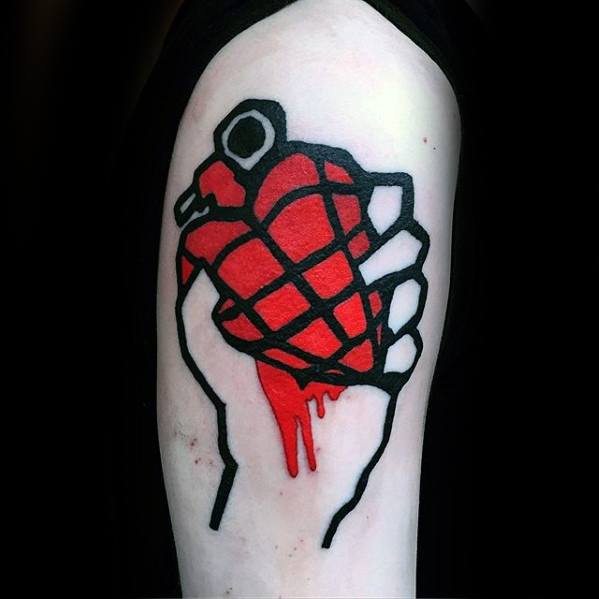 Tattoo of a hand gripping a red heart-shaped grenade with dripping blood, inspired by Green Day’s iconic *American Idiot* album cover.