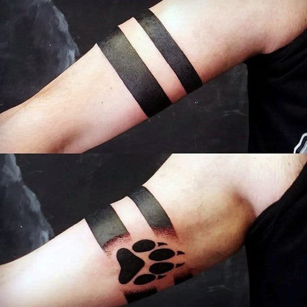 Arm tattoo featuring two black bands with a striking black wolf paw at the center