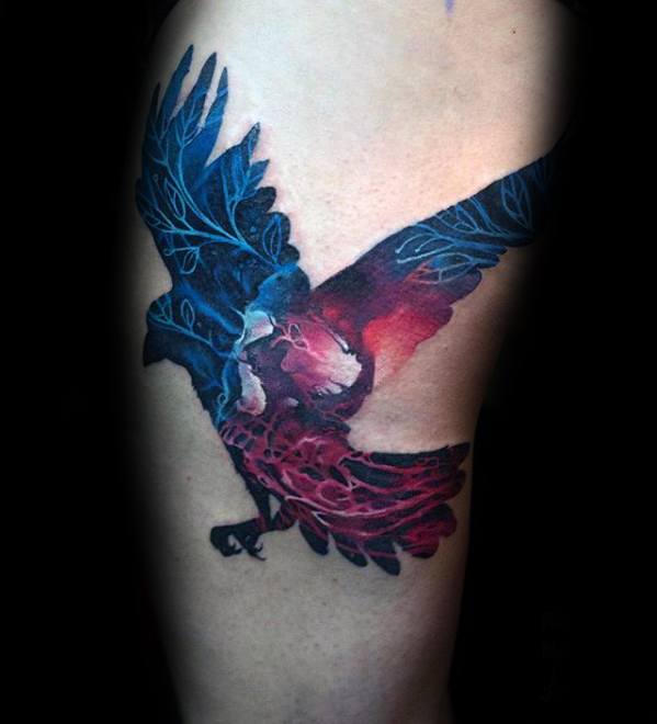 Vivid tattoo of a flying bird with blue and red wings, blending into a hidden skull at the center, symbolizing power and mortality.