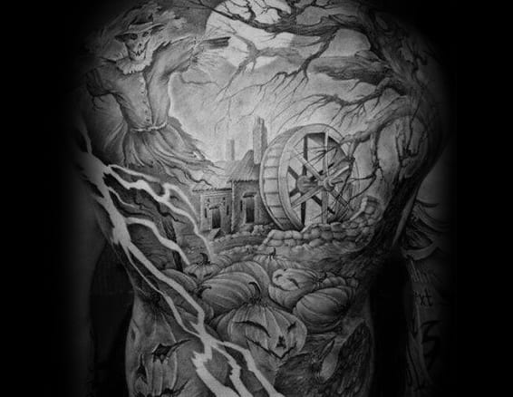 Back tattoo featuring a haunted mill with a large water wheel, twisted trees, lightning bolts, pumpkins, and a sinister scarecrow.