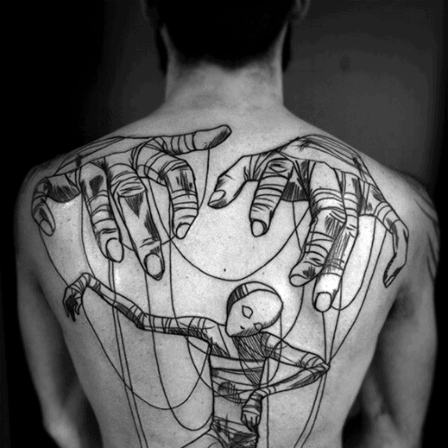 Bold blackwork puppet tattoo on the back featuring large hands manipulating a faceless marionette wrapped in strings and bandages.