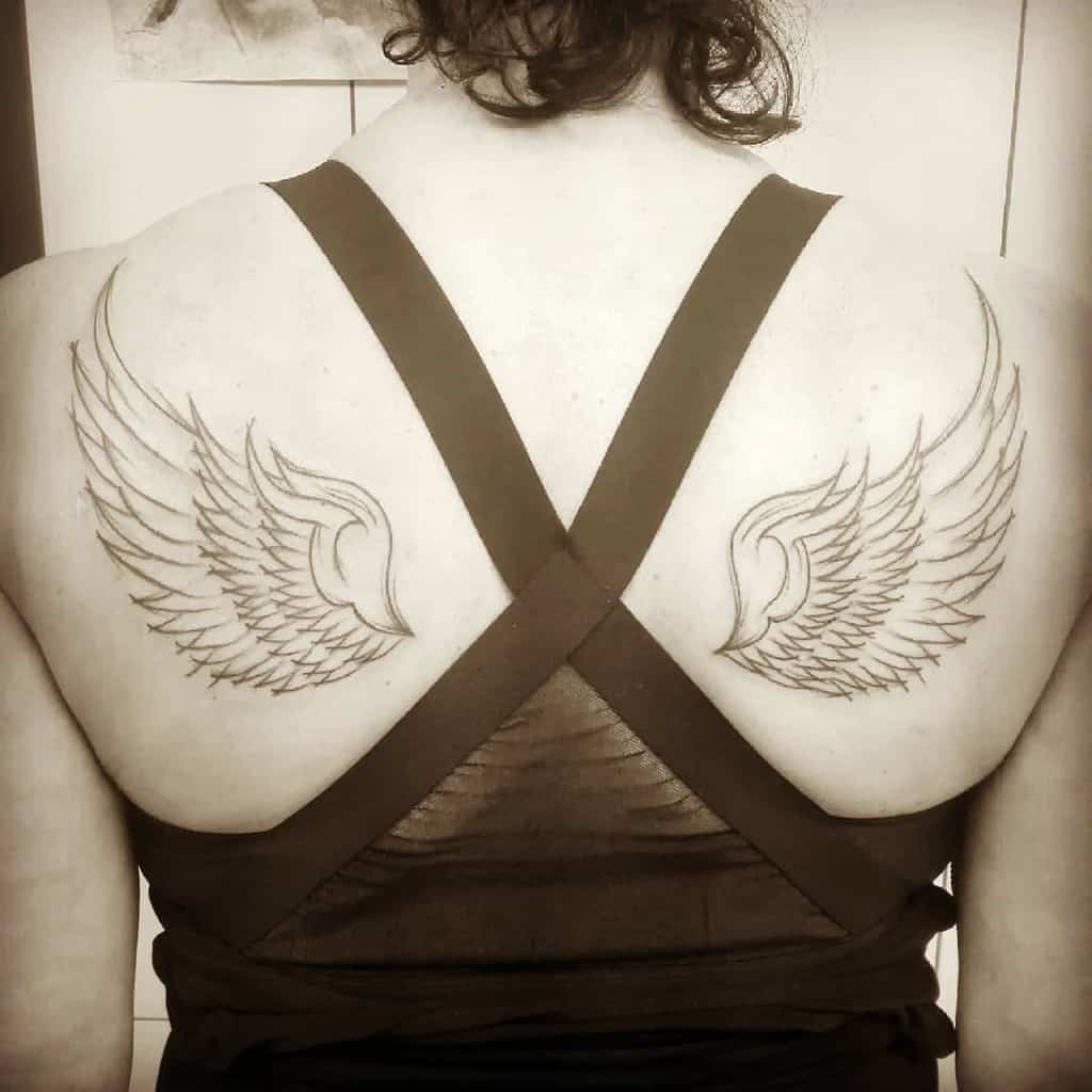 A pair of detailed angel wing tattoos symbolizing freedom, strength, and spirituality in a bold line design