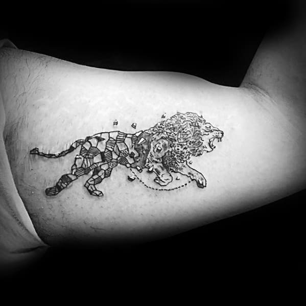 Roaring lion tattoo on the bicep with a dynamic split design—half realistic and half geometric blocks—creating a shattered transformation effect.