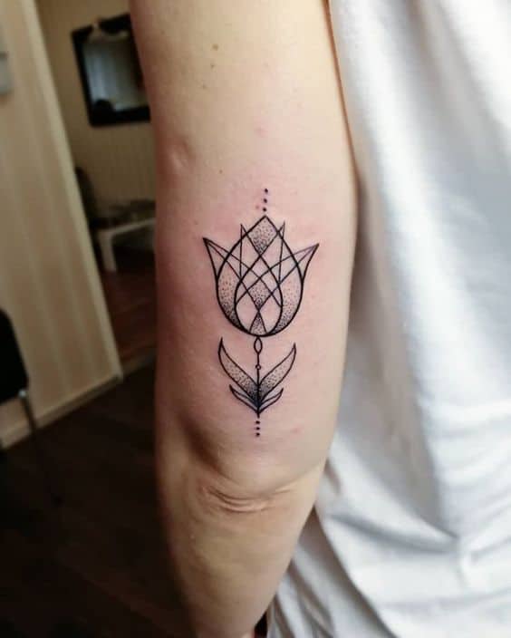 A geometric tulip tattoo on the upper arm, featuring intricate line work, net-like patterns, and decorative dot accents for a modern, artistic feel.