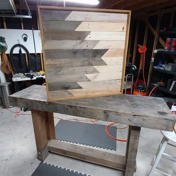 Geometric wooden wall art with chevron pattern, displayed on a rustic workbench.