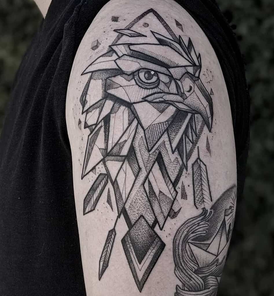 Geometric eagle tattoo on upper arm, featuring sharp lines and black ink shading