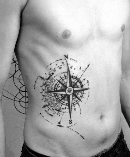 Abstract compass tattoo on the side of the torso with bold directional points and scattered digital-style dotwork.