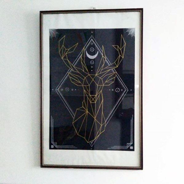 Framed geometric deer poster with gold lines and a crescent moon design.