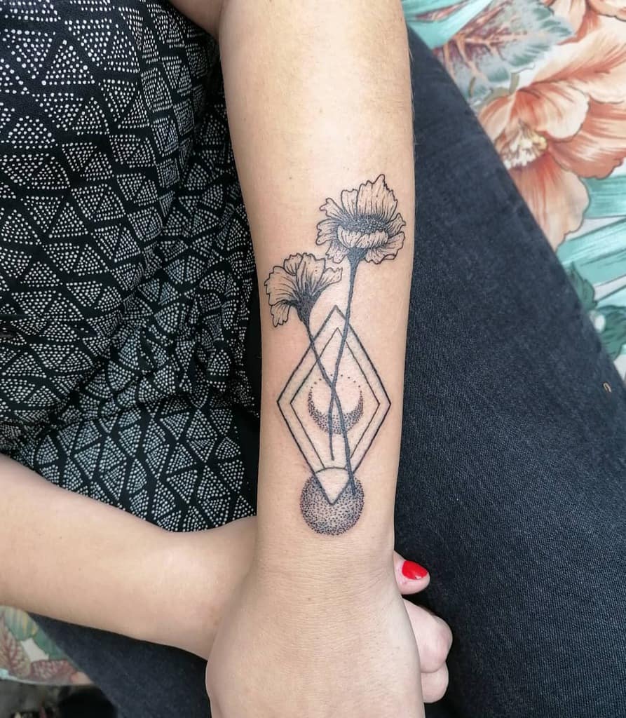 A forearm tattoo of geometric shapes and flowers in black ink