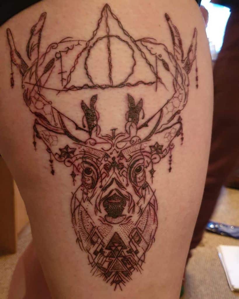 Intricate linework tattoo featuring a geometric stag with ornate antlers, the Deathly Hallows symbol, and delicate decorative details.