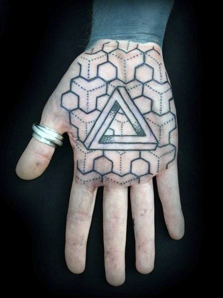 Hand with geometric tattoos, featuring hexagons and a triangle, with a silver ring