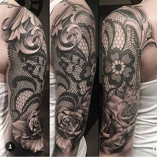 Black and grey full sleeve tattoo featuring intricate lace patterns, ornamental swirls, and realistic shaded roses for a bold, elegant look.