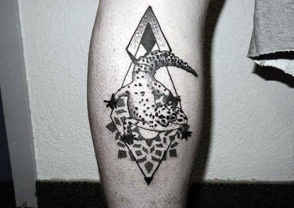 Bold gecko tattoo on calf with black geometric background, dotwork shading, and a realistic spotted lizard in the foreground.