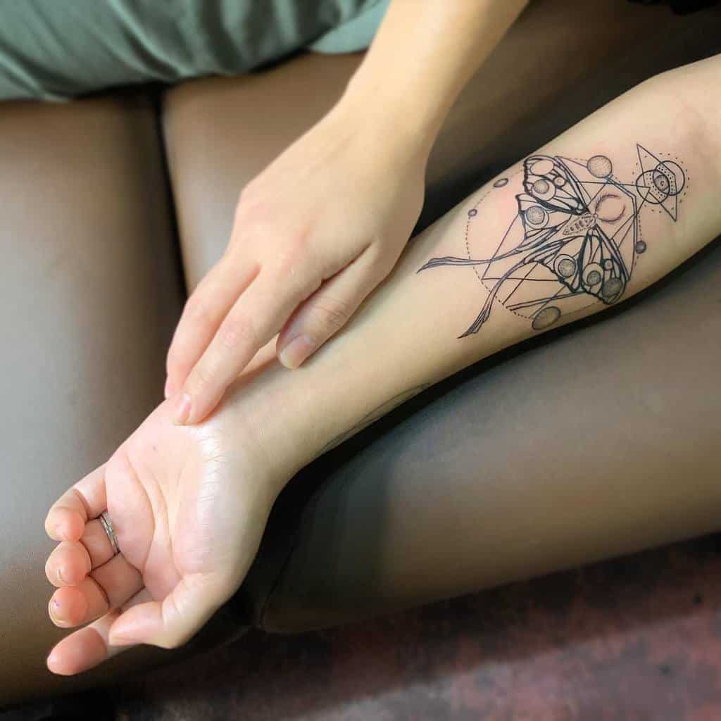 A geometric Luna Moth tattoo with intricate lines, circles, and celestial elements, featuring detailed black ink work
