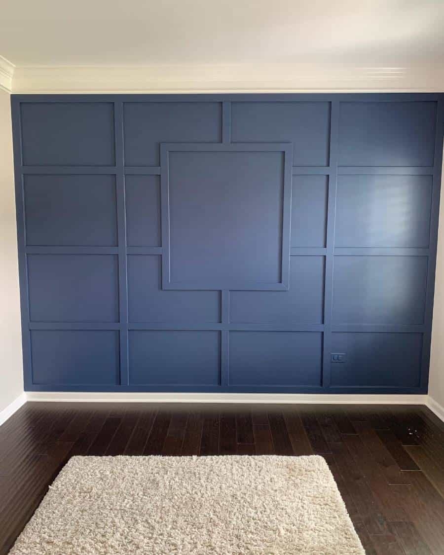 A blue accent wall complements dark wood flooring and a white rug